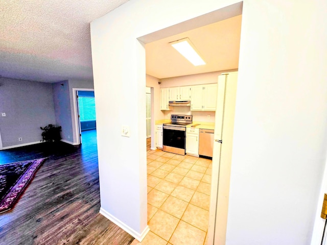 kitchen featuring baseboards, stainless steel electric range oven, under cabinet range hood, and dishwashing machine