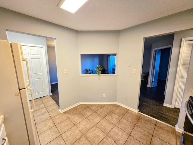 unfurnished room featuring light tile patterned flooring and baseboards