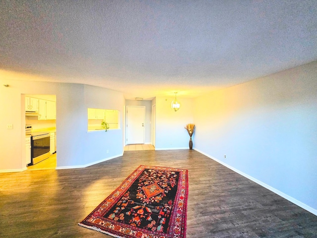 unfurnished room with a textured ceiling, baseboards, and wood finished floors