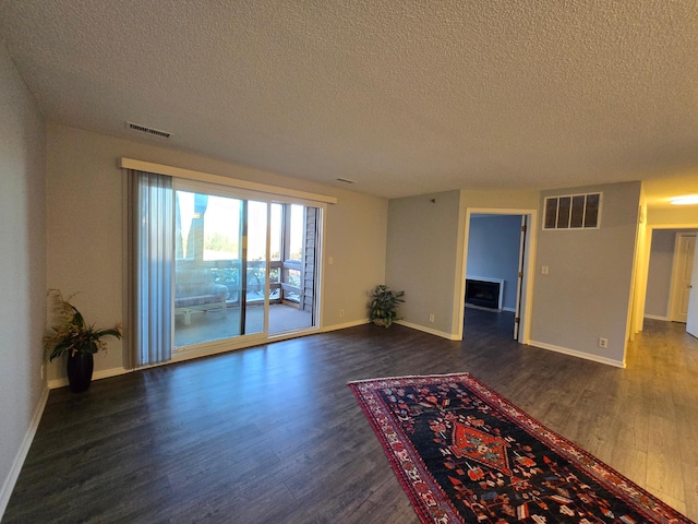 empty room with dark wood-style floors, baseboards, and visible vents