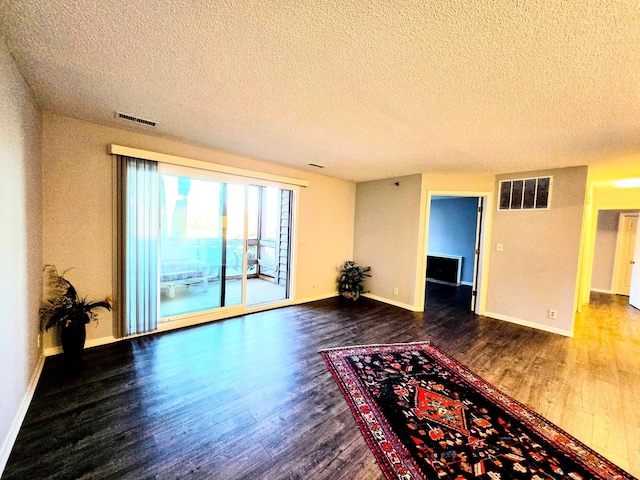 spare room featuring dark wood-style flooring, visible vents, and baseboards