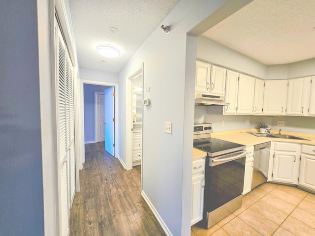 kitchen featuring under cabinet range hood, stainless steel appliances, a sink, white cabinetry, and light countertops