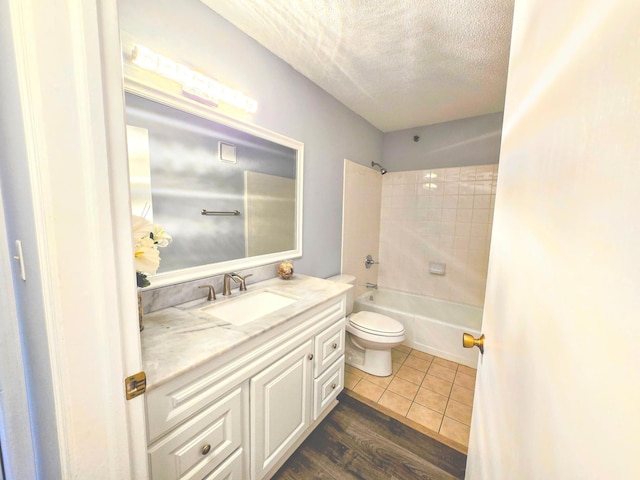 bathroom featuring shower / bath combination, toilet, a textured ceiling, vanity, and tile patterned floors