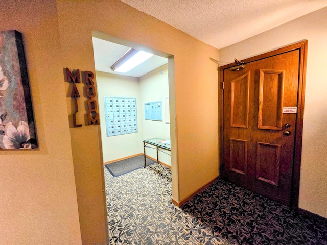 hallway with a textured ceiling, carpet floors, and baseboards