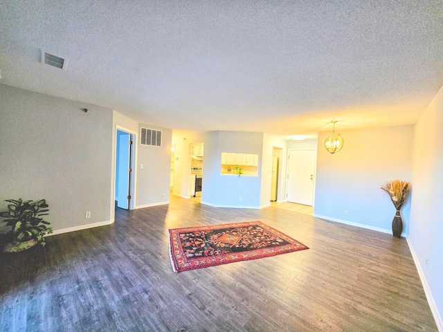 living area featuring a chandelier, wood finished floors, visible vents, and baseboards