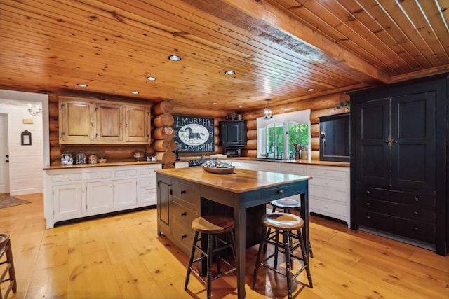 kitchen featuring light wood finished floors, wooden ceiling, log walls, a kitchen bar, and wooden counters