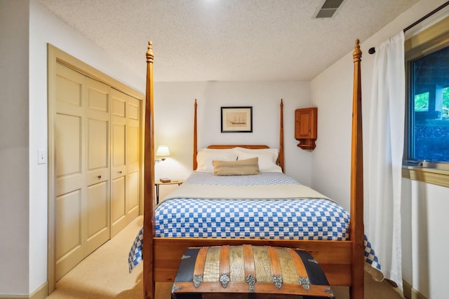 bedroom with a closet, visible vents, a textured ceiling, and carpet flooring