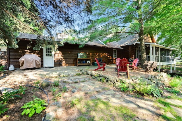 back of property featuring a patio, an outdoor fire pit, and a sunroom