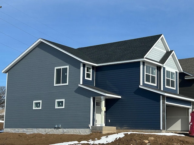 traditional home featuring a garage and roof with shingles