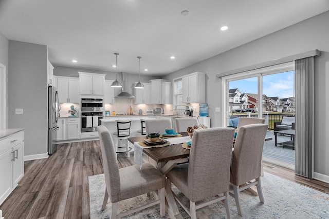 dining space featuring baseboards, wood finished floors, and recessed lighting