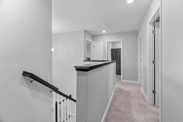 corridor featuring recessed lighting, baseboards, light colored carpet, and an upstairs landing