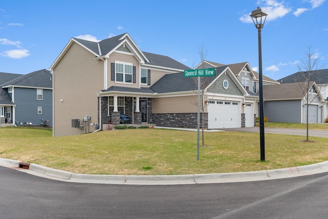 craftsman-style house with driveway, stone siding, and a front yard