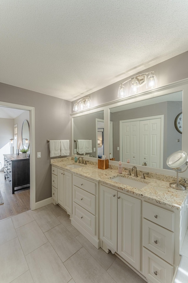 bathroom featuring a textured ceiling, double vanity, and a sink