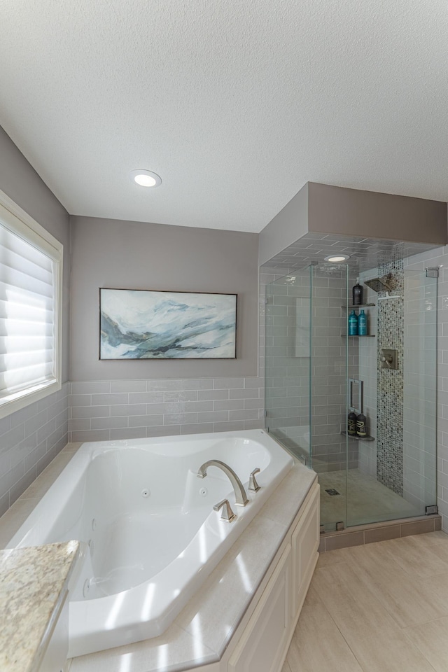 bathroom featuring a shower stall, a whirlpool tub, and a textured ceiling