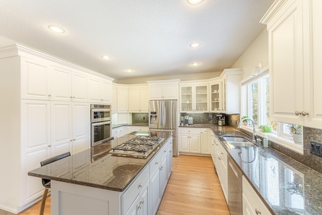 kitchen featuring stainless steel appliances, decorative backsplash, a sink, a kitchen breakfast bar, and a center island