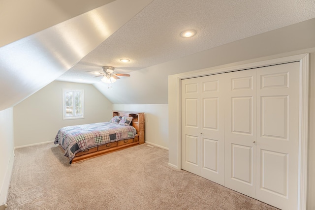 carpeted bedroom with a textured ceiling, a closet, baseboards, ceiling fan, and vaulted ceiling