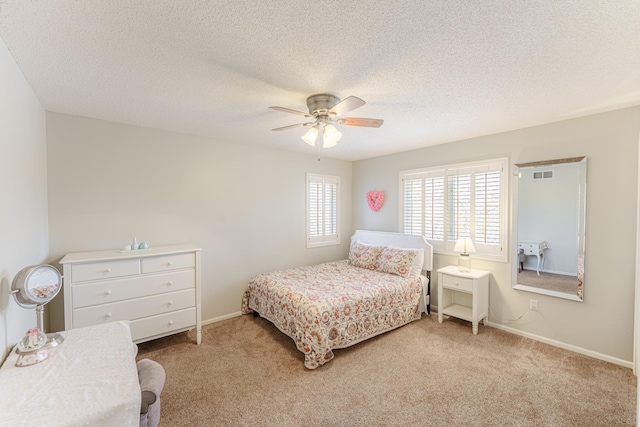 carpeted bedroom with visible vents, baseboards, a textured ceiling, and ceiling fan