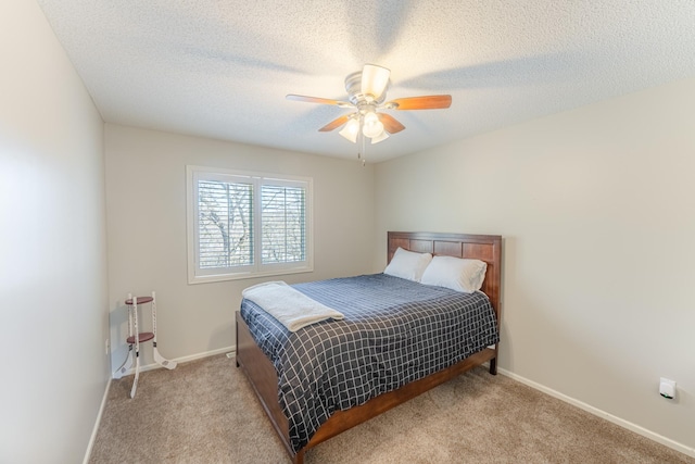 bedroom featuring baseboards, light colored carpet, a ceiling fan, and a textured ceiling