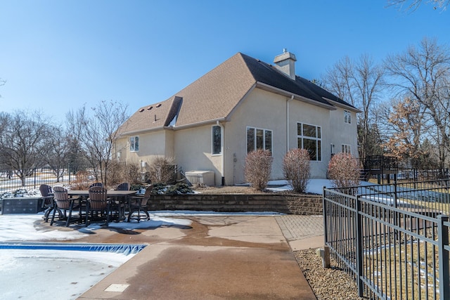 rear view of house featuring fence, outdoor dining area, a chimney, stucco siding, and a patio area