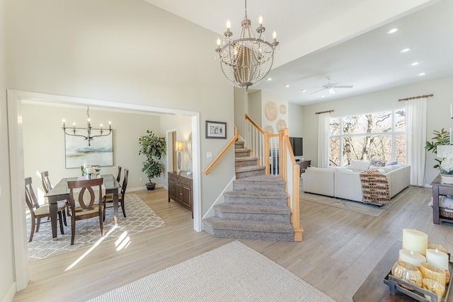 interior space featuring baseboards, light wood finished floors, recessed lighting, stairs, and ceiling fan with notable chandelier