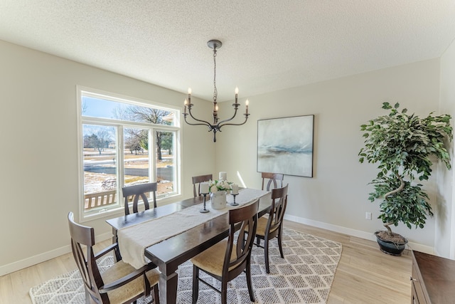 dining room featuring a notable chandelier, baseboards, light wood-style floors, and a textured ceiling