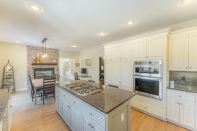 kitchen featuring white cabinets, light wood-type flooring, appliances with stainless steel finishes, and a kitchen island