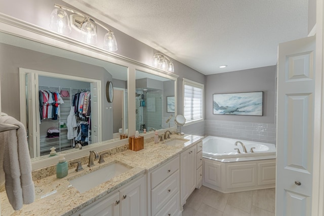 full bath with a textured ceiling, double vanity, a stall shower, and a sink