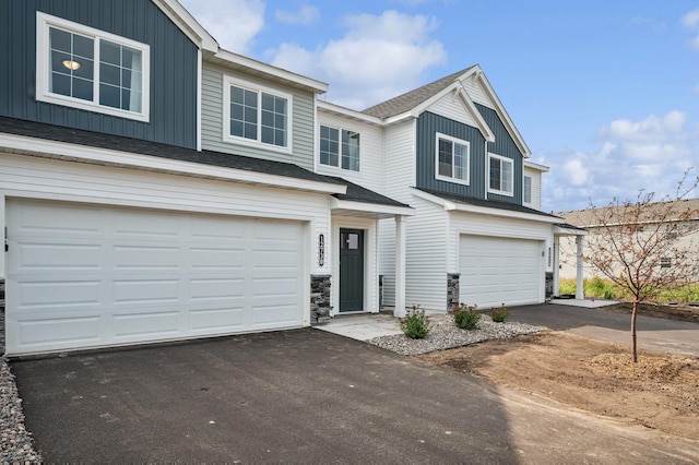 view of front of property with a garage, driveway, board and batten siding, and roof with shingles