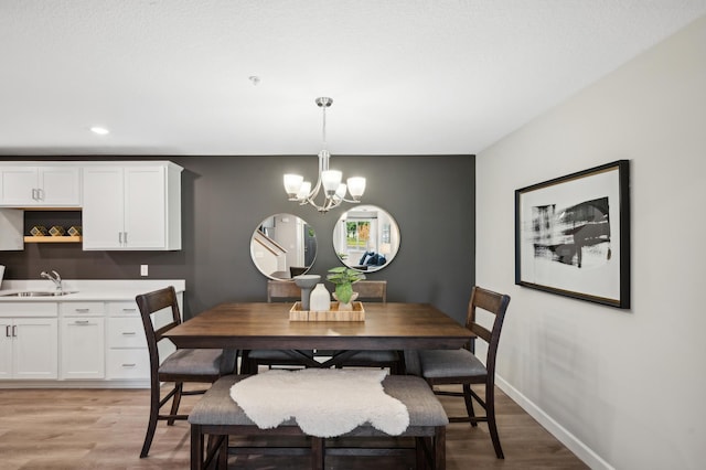 dining area with a chandelier, light wood finished floors, and baseboards