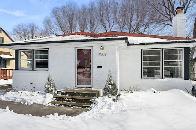 view of front of house with brick siding and a chimney