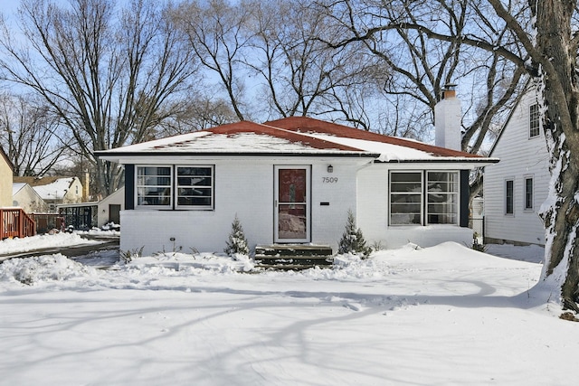 bungalow-style home with brick siding and a chimney