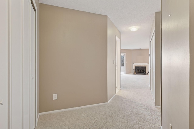 corridor featuring baseboards, carpet floors, and a textured ceiling