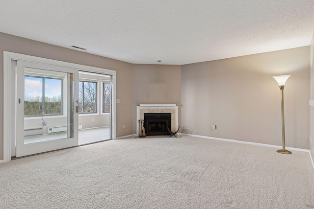 unfurnished living room with carpet, visible vents, baseboards, a fireplace, and a textured ceiling