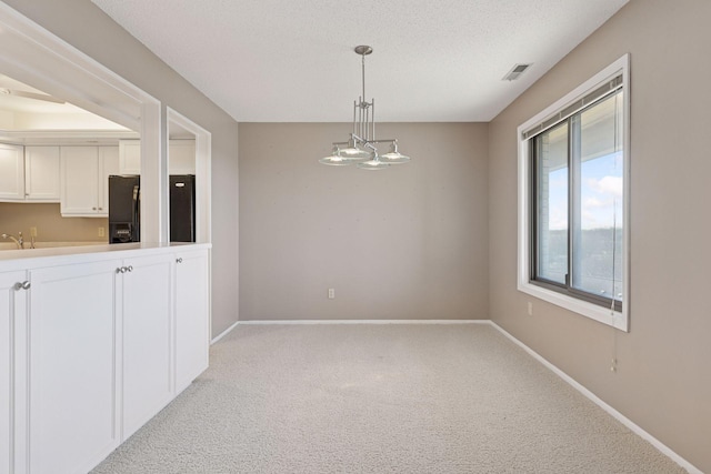 unfurnished dining area featuring light carpet, visible vents, a textured ceiling, and baseboards