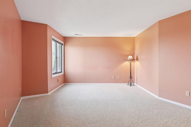 empty room with visible vents, baseboards, carpet, and a textured ceiling