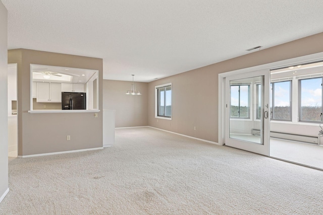 unfurnished living room featuring visible vents, light carpet, a baseboard heating unit, a textured ceiling, and baseboards