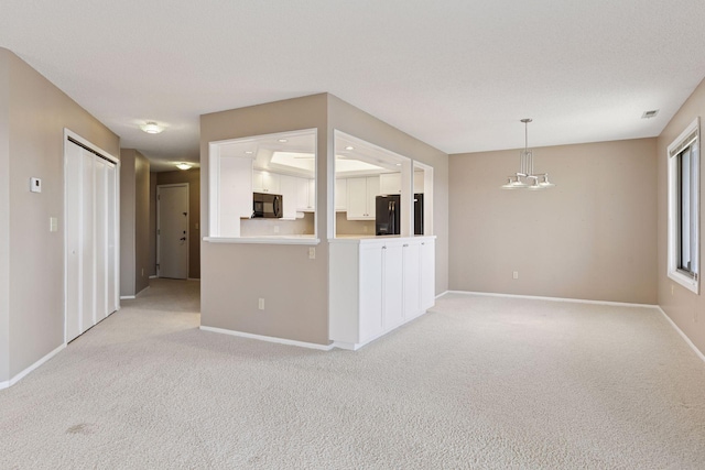 unfurnished living room featuring light colored carpet, baseboards, and a chandelier