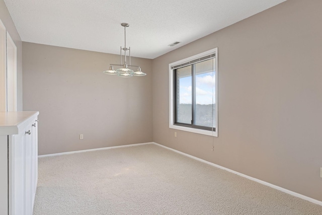 carpeted empty room with baseboards, visible vents, and a textured ceiling