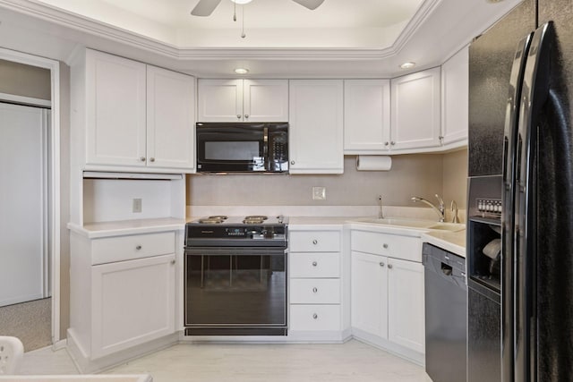 kitchen with a sink, black appliances, white cabinets, and light countertops