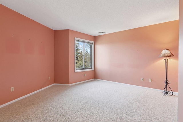 unfurnished room with visible vents, baseboards, carpet floors, and a textured ceiling