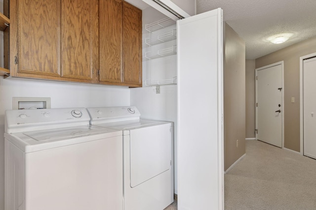 washroom featuring a textured ceiling, baseboards, cabinet space, light carpet, and washer and dryer