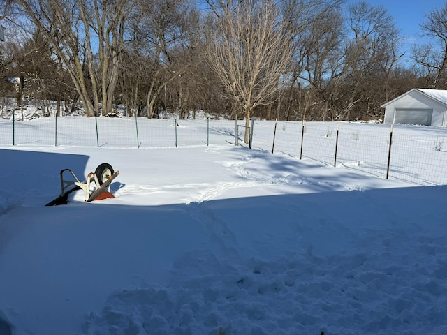 yard layered in snow with a detached garage and fence