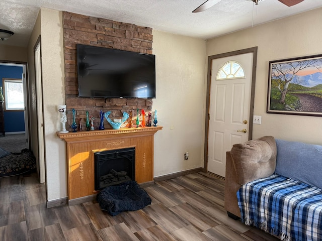 living room featuring a fireplace, a textured ceiling, and wood finished floors