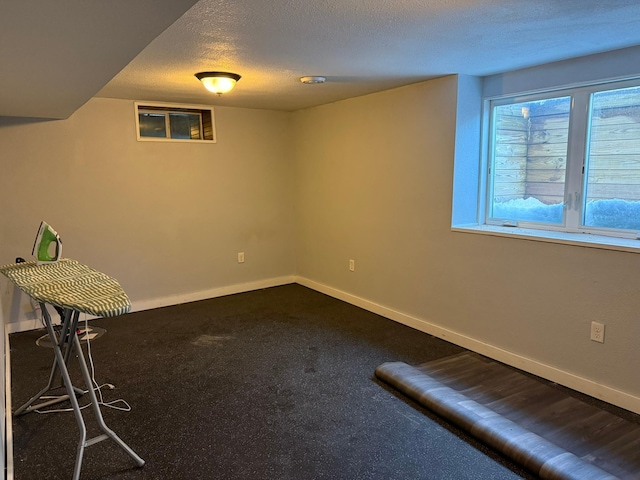 below grade area with carpet, a textured ceiling, and baseboards