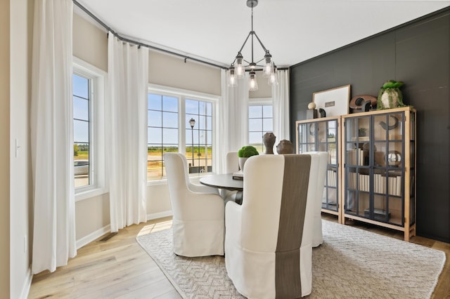 dining space featuring baseboards, light wood finished floors, and an inviting chandelier