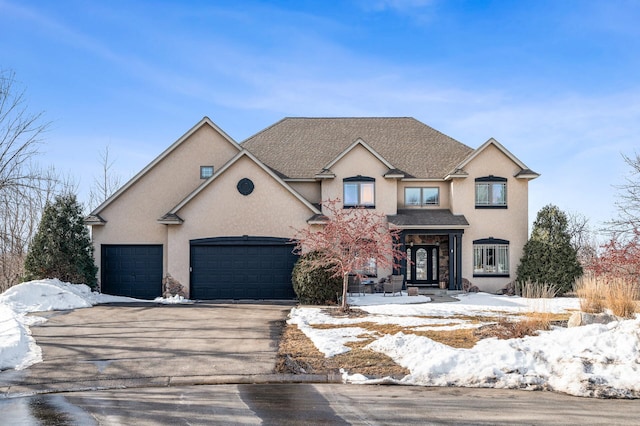 traditional-style home featuring stucco siding, an attached garage, concrete driveway, and roof with shingles