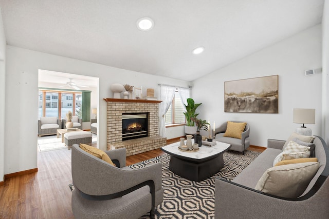 living room with lofted ceiling, a healthy amount of sunlight, a fireplace, and wood finished floors