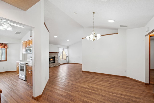 interior space with visible vents, electric stove, stainless steel microwave, vaulted ceiling, and a fireplace