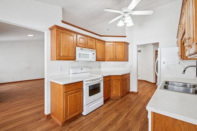 kitchen with white appliances, wood finished floors, a sink, light countertops, and brown cabinetry