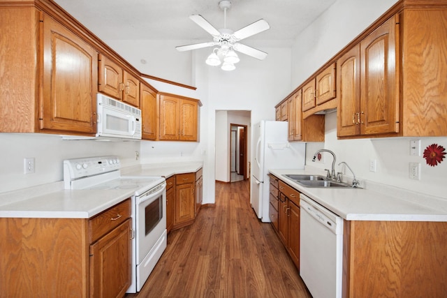 kitchen featuring white appliances, dark wood-style floors, brown cabinets, and a sink